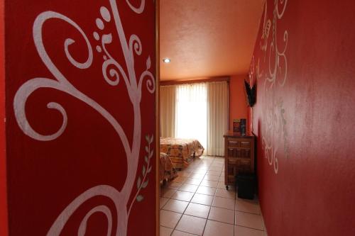 a room with a red wall and a room with a bed at Hotel Real de la Sierra in Mazamitla