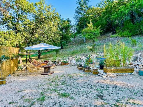 a patio with an umbrella and a table and chairs at Histoire de cru in Saignon