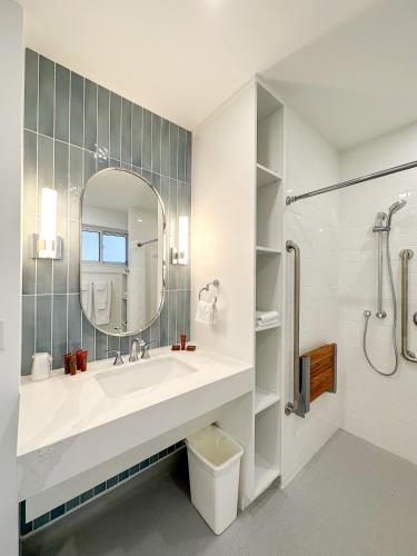 a bathroom with a sink and a shower and a mirror at Oasis by the Bay Vacation Suites in Wasaga Beach