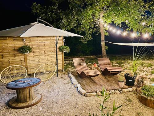 a patio with chairs and a table and an umbrella at Histoire de cru in Saignon