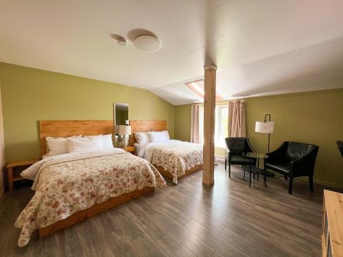 a hotel room with two beds and a table and chairs at Auberge la Rosepierre bistro Henri in Grandes-Bergeronnes