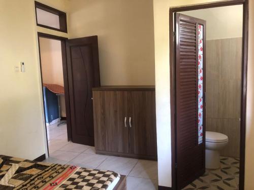 La salle de bains est pourvue de toilettes et d'une porte en bois. dans l'établissement Hotel Pantai Mutiara, à Pelabuhan Ratu