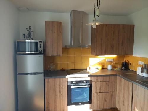 une cuisine avec des armoires en bois et un réfrigérateur en acier inoxydable dans l'établissement La chalossaise, à Saint-Paul-lès-Dax