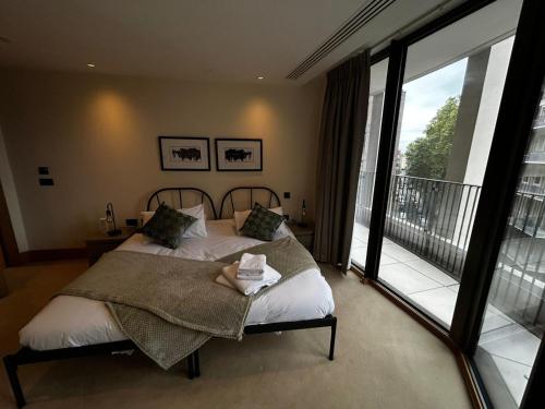 a bedroom with a large bed and a balcony at Luxury 2BR Apt at C House Near Buckingham Palace in London