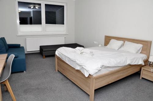 a bedroom with a large bed and a blue couch at Pokoje, Apartamenty, Restauracja Marcus in Oborniki
