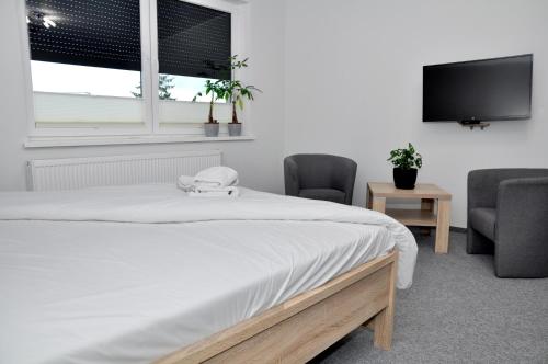 1 dormitorio con 1 cama con 2 sillas y TV de pantalla plana en Pokoje, Apartamenty, Restauracja Marcus, en Oborniki