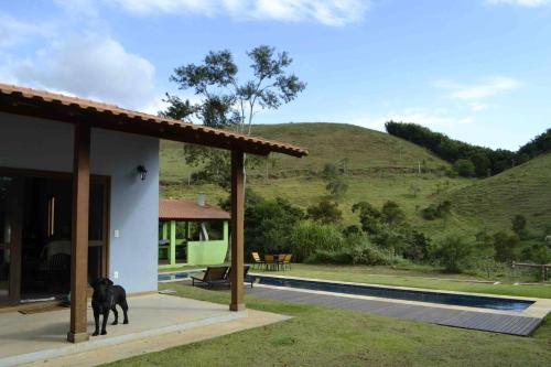 Ein schwarzer Hund steht vor einem Haus. in der Unterkunft Casa de campo com piscina no Vale das Videiras in Petrópolis