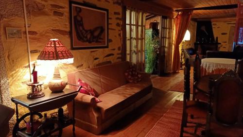 una sala de estar con sofá y una lámpara en una mesa. en Quinta do Cavaco en Lázaro