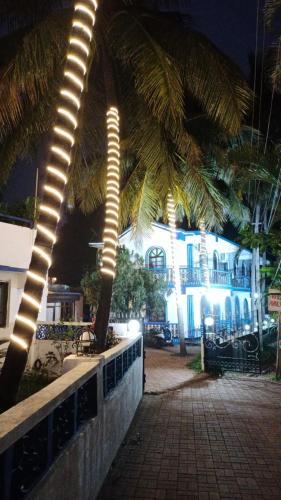 a palm tree with lights in front of a building at Baga Beach Crystal in Baga