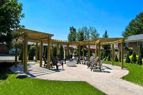 a patio with chairs and a wooden pergola at Oasis by the Bay Vacation Suites in Wasaga Beach