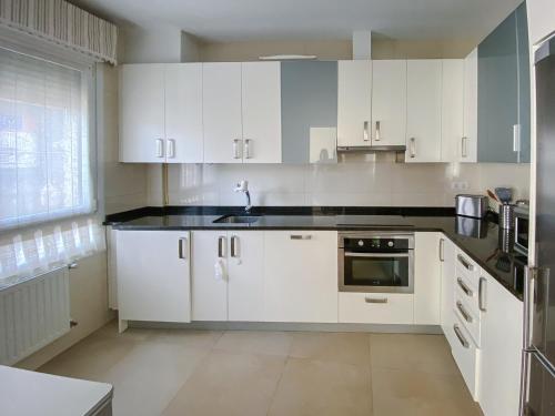una cocina con armarios blancos y fregadero en Piso nuevo y espacioso en el centro de Mundaka, en Mundaka