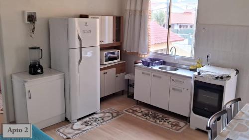 cocina con nevera, fregadero y ventana en Sobrado Praia dos Ingleses, en Florianópolis