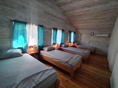 a room with three beds and blue curtains at Tierra Verde Bed & Breakfast in Bocas del Toro
