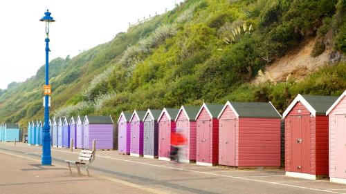 a row of colorful beach huts next to a hill at Self-contained flat, off street parking close to town and beach in Bournemouth