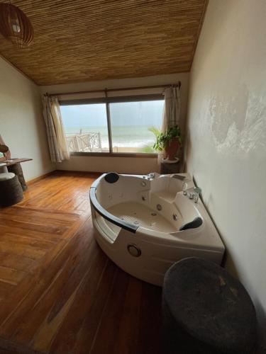a bath tub sitting in a room with a window at Villas Badiene in Poponguine
