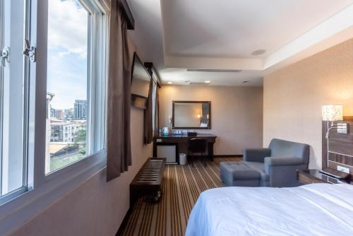 a hotel room with a bed and a chair and a window at Hub Hotel - Zhongshan Branch in Taipei