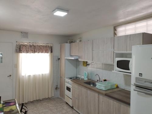 Una pequeña cocina con fregadero y microondas. en Departamento Carrodilla Luján, en Ciudad Lujan de Cuyo