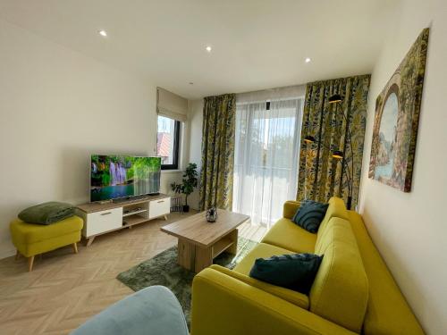 a living room with a yellow couch and a tv at Luxury City Retreat with Terrace in Košice