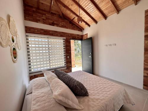 a bedroom with a bed with pillows and a window at Casa Roca con piscina Hospedaje Campestre in Los Santos
