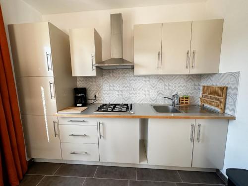 a kitchen with white cabinets and a sink at Le Tipani in Vernon