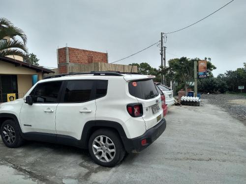 uma SUV branca estacionada num parque de estacionamento em QUARTO COM COZINHA E CHURASQUEIRA INDIVIDUAL. em Passo de Torres