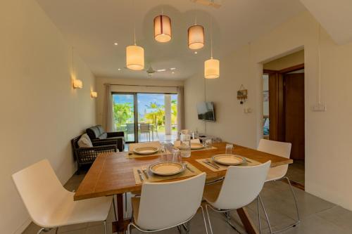 uma sala de jantar com uma mesa de madeira e cadeiras brancas em Stella Marris beachfront villa em Pointe aux Sable
