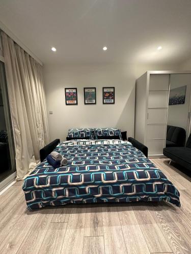 a bedroom with a large bed with a blue comforter at Modern flat in Victoria in London