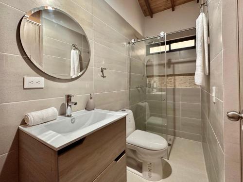 y baño con lavabo, aseo y espejo. en Casa Roca con piscina Hospedaje Campestre, en Los Santos