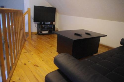 ein Wohnzimmer mit einem Sofa, einem Tisch und einem TV in der Unterkunft Appartement RDC dans jolie parc Arboré in Beure