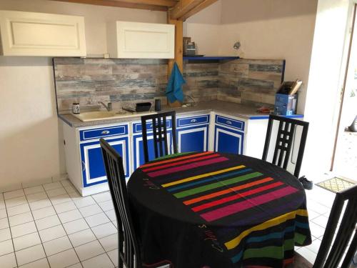 eine Küche mit einem Tisch und einer bunten Decke darauf in der Unterkunft Appartement RDC dans jolie parc Arboré in Beure