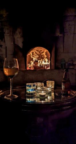 a table with a glass of wine and a fireplace at Lemoniegites in Lemonie