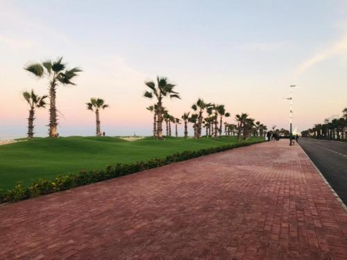 una strada in mattoni con palme e un campo da golf di Port Said city, Damietta Port Said coastal road num2996 a Port Said