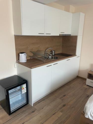 a kitchen with white cabinets and a sink and a microwave at Teddy Apartment in Veliko Tŭrnovo