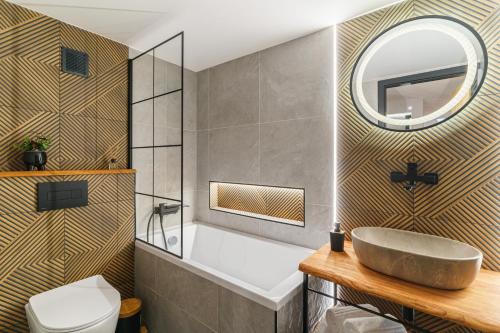 a bathroom with a sink and a tub and a mirror at MovieCity Apartament Piotrkowska 92 in Łódź