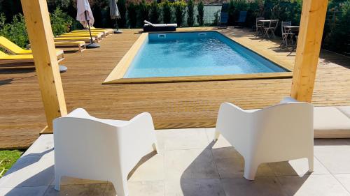 una piscina con 2 sillas blancas junto a una terraza en Chalé do Vale, en Pinhal Novo