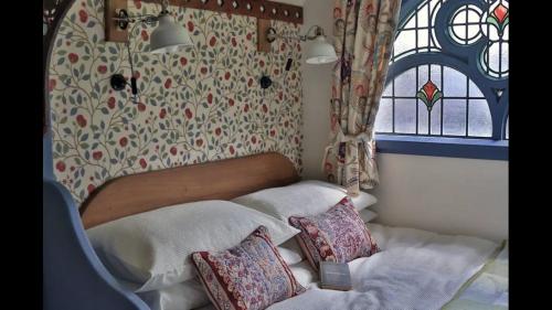 um quarto com uma cama com almofadas e uma janela em Magical Tabernacle in a Beautiful Setting with Hot Tub em Bude