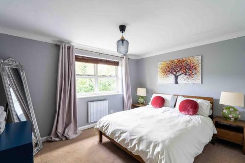 a bedroom with a bed with red pillows and a tree at Quiet 2 bed flat in SW London Parking Inc in Teddington