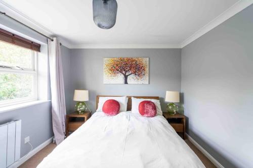 - une chambre avec un lit et 2 oreillers rouges dans l'établissement Quiet 2 bed flat in SW London Parking Inc, à Teddington