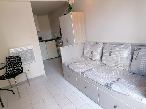 Habitación con cama con almohadas y cocina. en Superbe studio proche de toutes commodités, en Franqueville-Saint-Pierre