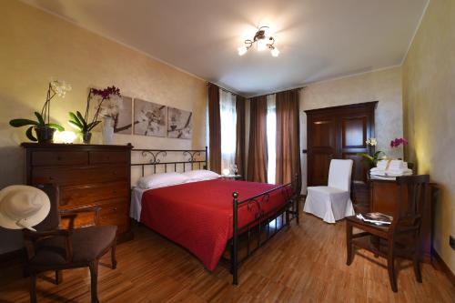 um quarto com uma cama vermelha, uma secretária e cadeiras em Villa Vecchio em Castagnito