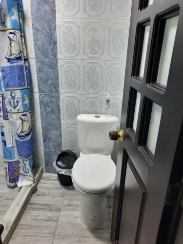ein weißes WC im Bad mit Tür in der Unterkunft Casa Central, primer piso in Norcasia