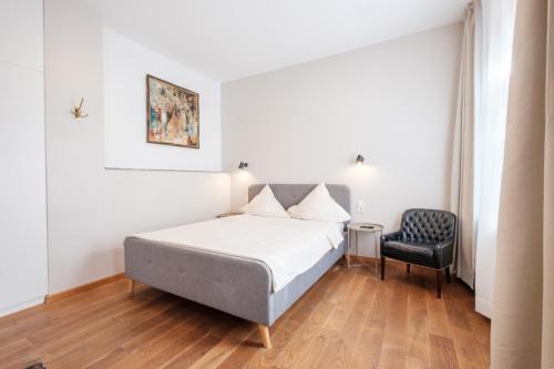 ein Schlafzimmer mit einem Bett und einem Stuhl in der Unterkunft Zaunkönig Apartments in Baden-Baden