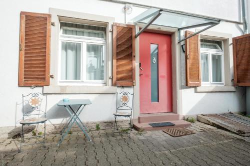 a house with a red door and chairs outside at Zaunkönig Apartments in Baden-Baden
