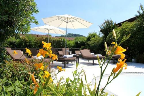 a garden with chairs and umbrellas and flowers at Joia Hotel & Luxury Apartments RTA in Brusaporto