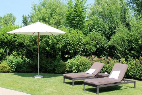 two chairs and an umbrella in the grass at Joia Hotel & Luxury Apartments RTA in Brusaporto