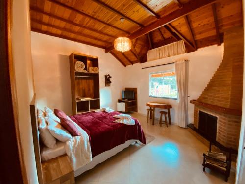 een slaapkamer met een bed en een open haard bij Pousada D'avilas in Monte Verde