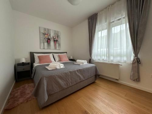a bedroom with a bed with pink pillows and a window at Thyke Apartment in Krapinske Toplice