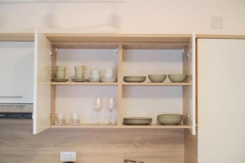 a cabinet filled with bowls and plates and wine glasses at Thyke Apartment in Krapinske Toplice