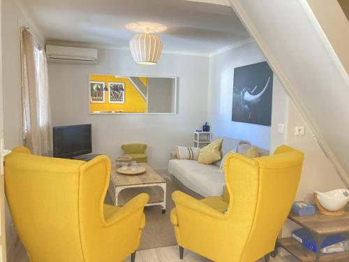 a living room with yellow chairs and a couch at Maison de vacances face à la mer in Saint Pierre La Mer