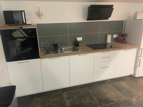 a kitchen with white cabinets and a black microwave at Gare australe in Saint-Brieuc